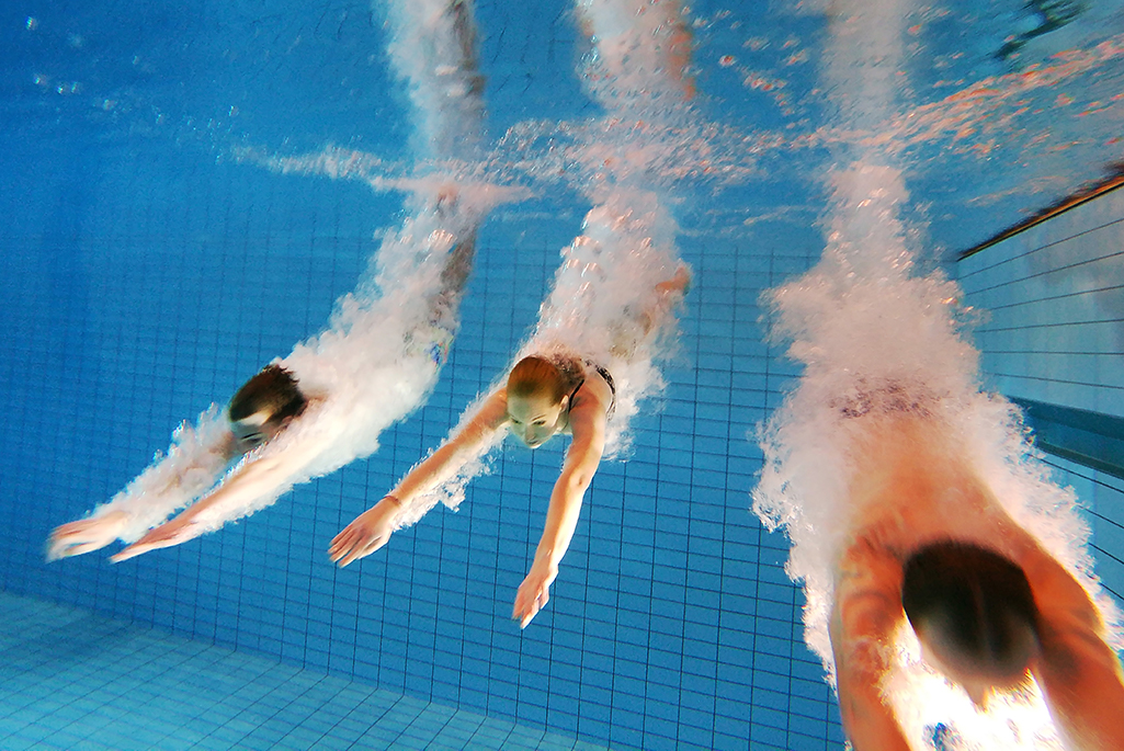 Foto på tre personer under vatten som precis dykt ner. Foto: Per Groth