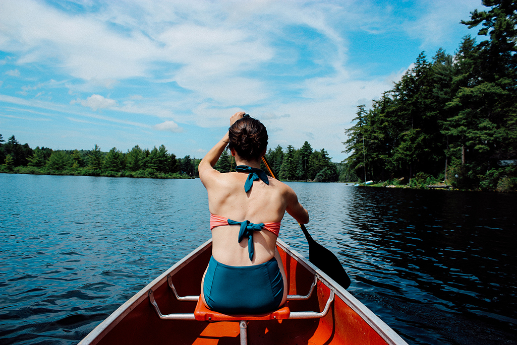 Foto på en kvinnas rygg som sitter i en kajak och paddlar.