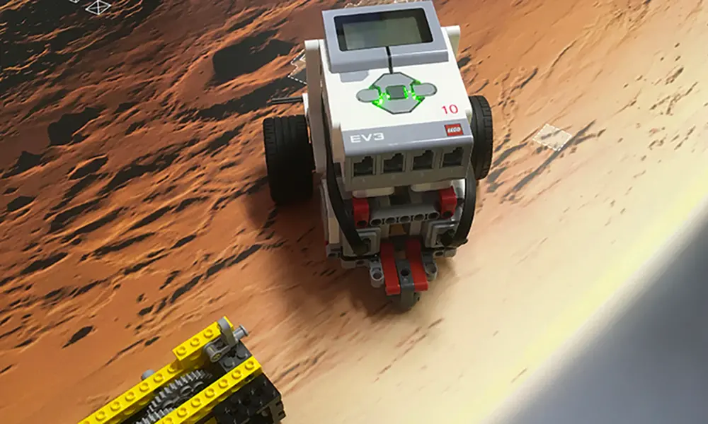 Foto på lego-robot som ser ut att köra på planeten Mars.