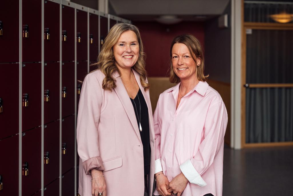 Två kvinnor i rosa kläder tittandes in i kameran.
