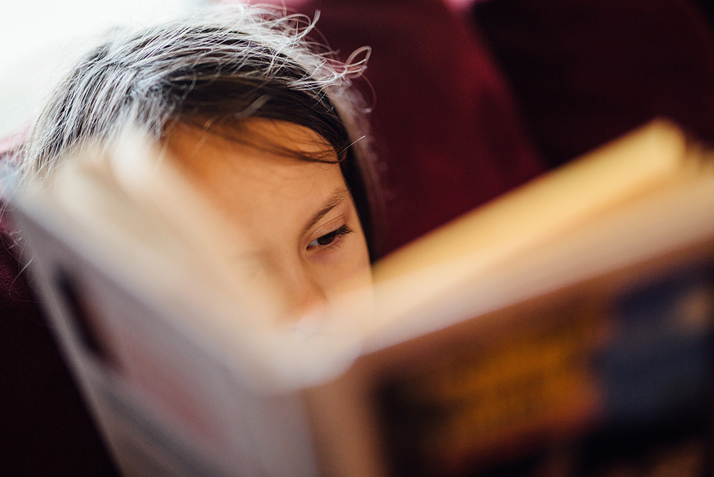 Foto på en tjej som läser en bok.