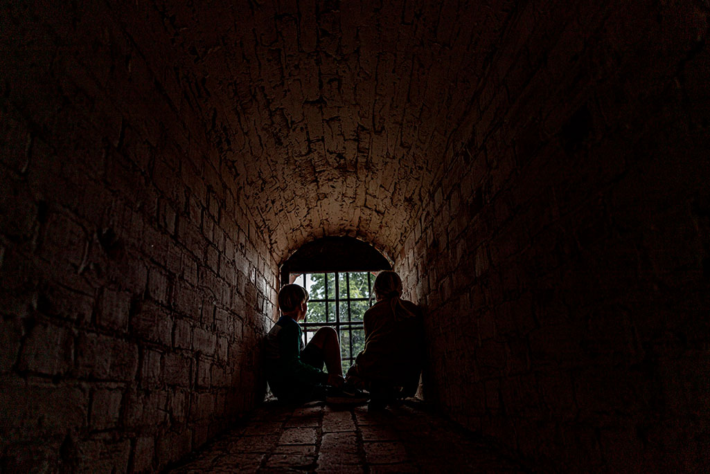 Foto på två personer som sitter i ett fönster i en fängelsehåla.