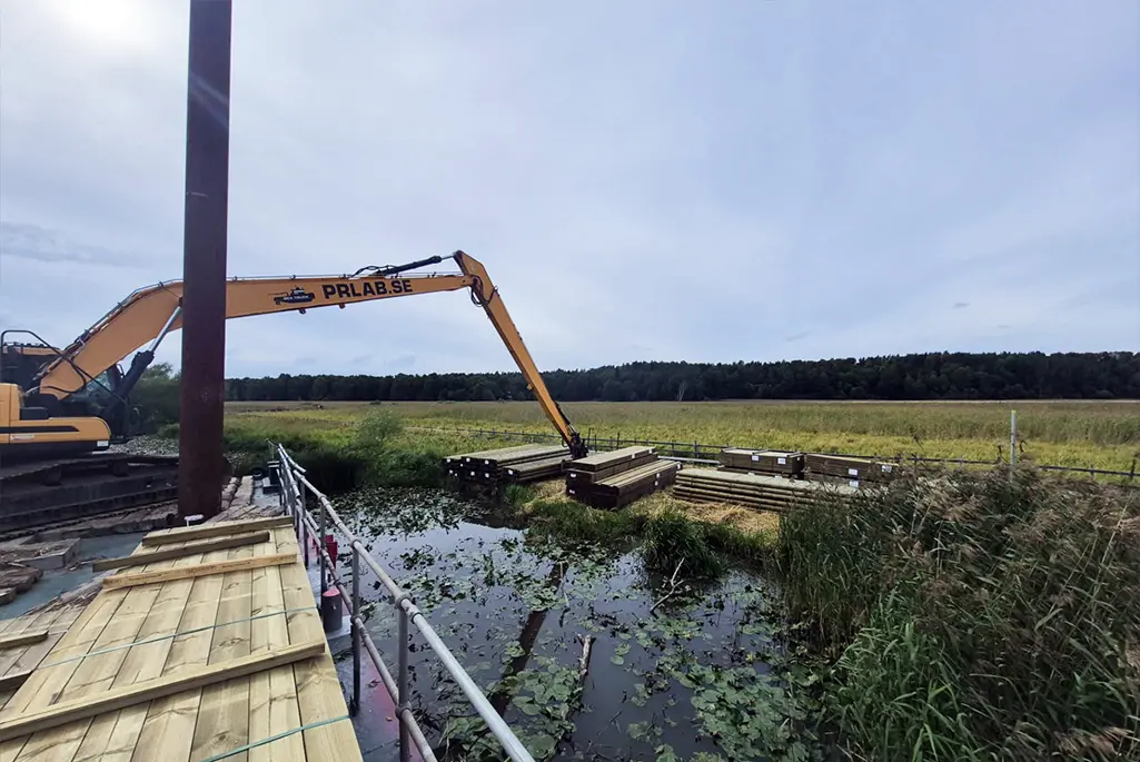 Röd pråm lastar virke vid hamn