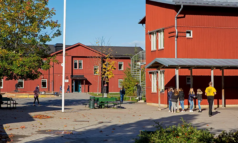 Foto av Örsundsbroskolan. Det är flera byggnader i rödmålat trä.