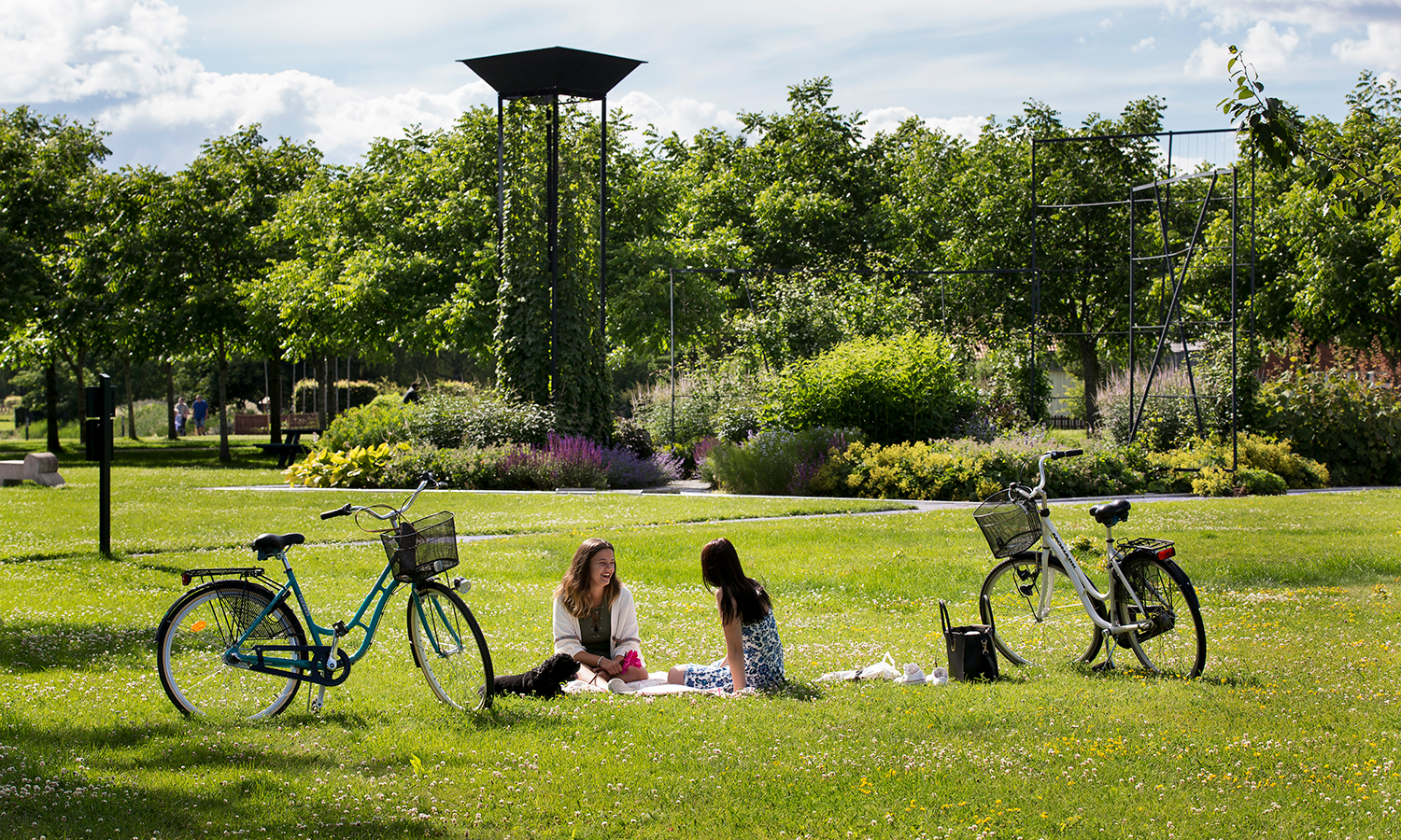 Personer som sitter och vilar vid Blå Trädgård på Åpromenaden med sina cyklar. 