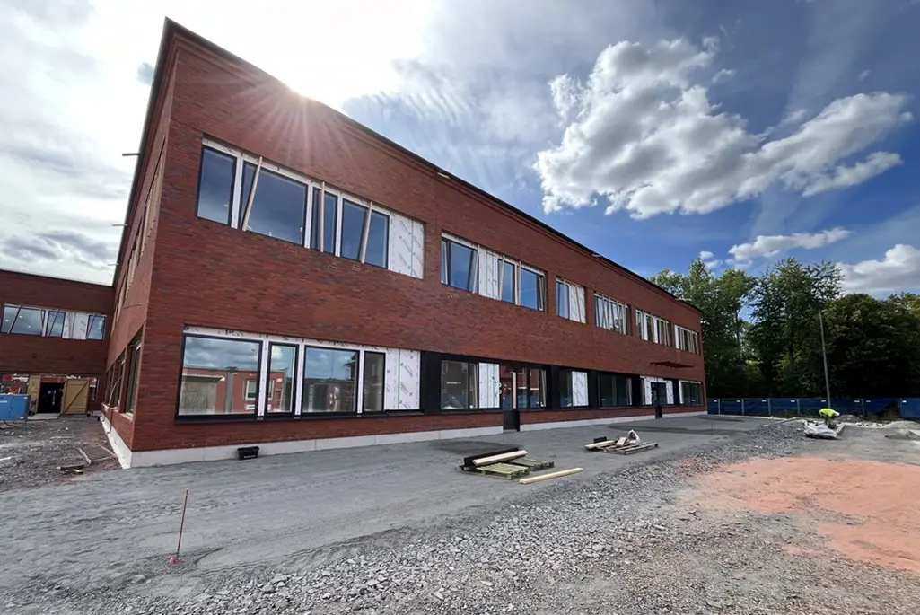 Tegelbyggnad med stora fönster i ett byggområde.