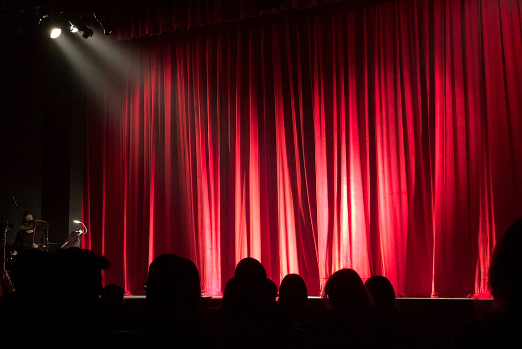 Bild på en scen där det hänger ett rött draperi.